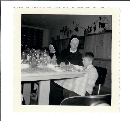La foto in bianco e nero mostra Beni Freudiger all'età di sette anni, mentre guarda il suo nido di Pasqua. È seduto a tavola con una sorella accanto a lui. Sullo sfondo, un'altra sorella è seduta con altri bambini.